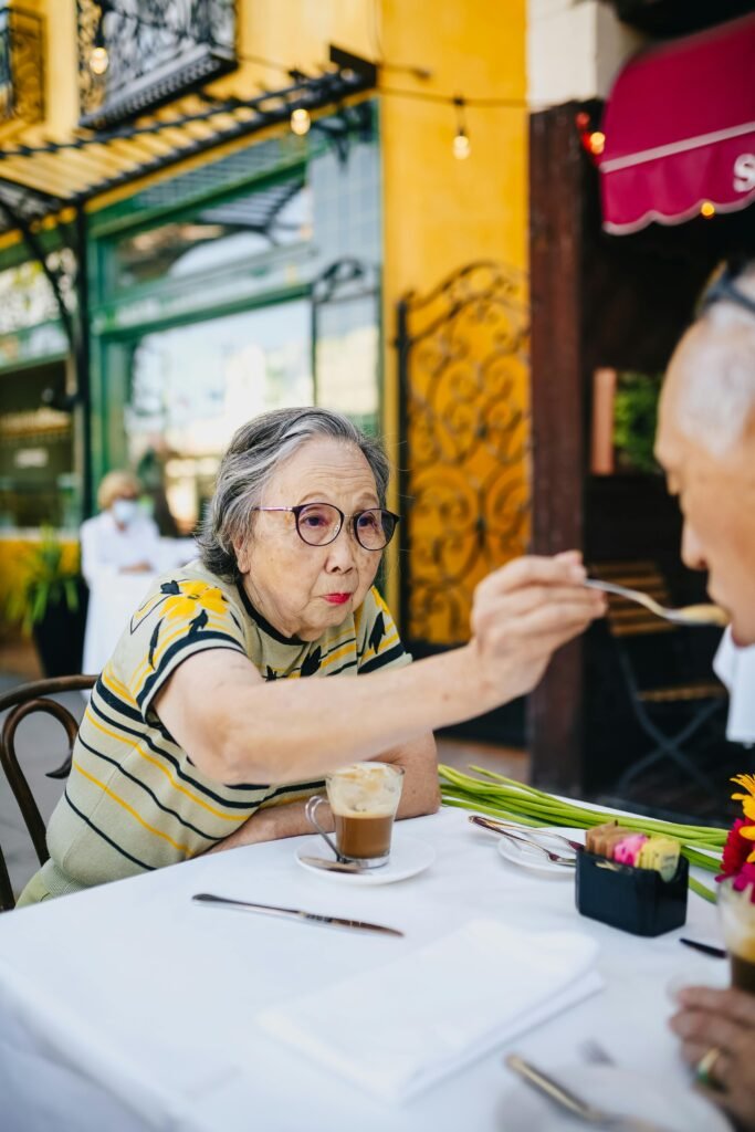 pexels-photo-5637706-5637706 Senior Asian couple sharing a moment at a vibrant outdoor cafe, enjoying coffee together.